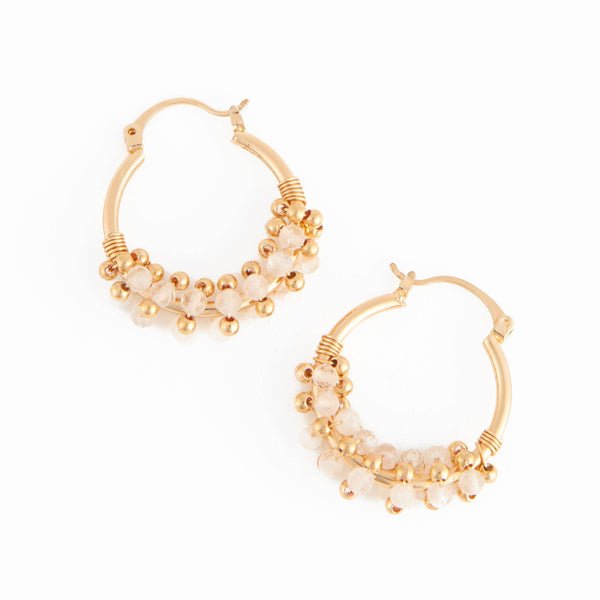 gold hoop earrings with dainty white and gold beads on the bottom half of the hoop